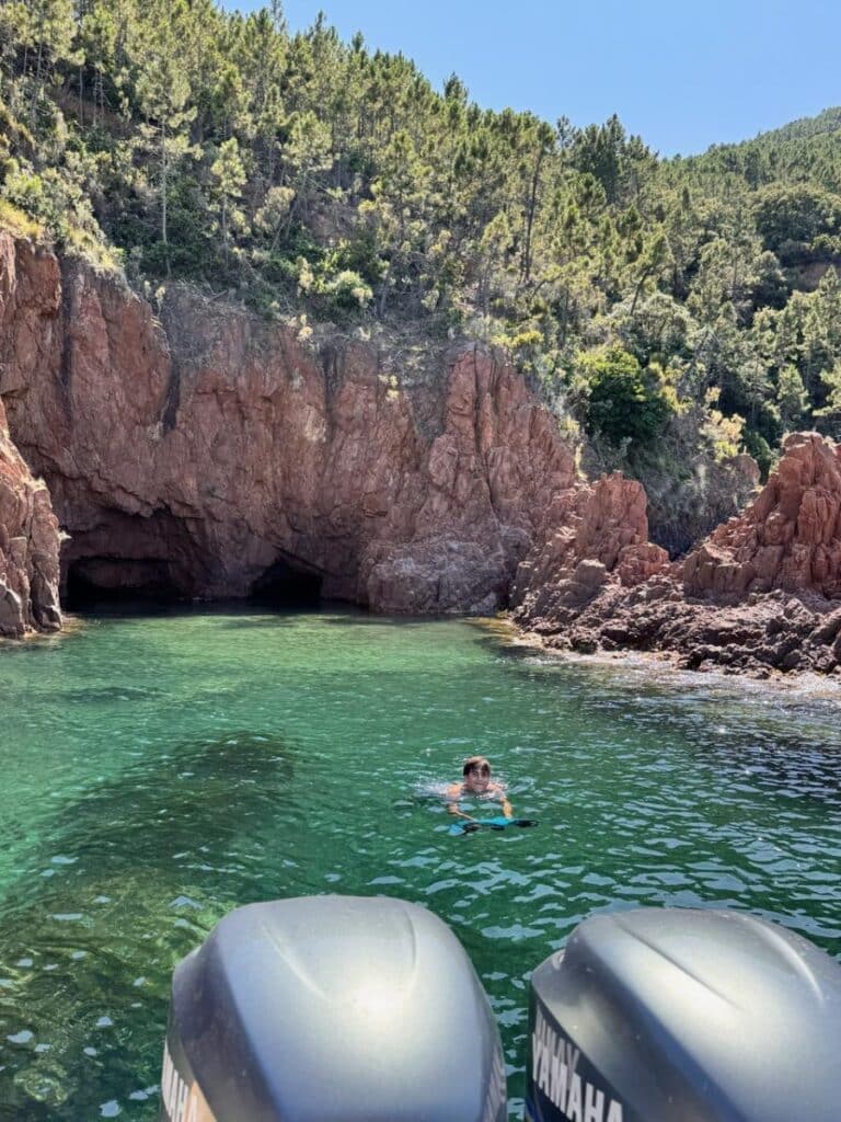 Nageur avec Seabob dans l'eau turquoise près de falaises rouges et grottes marines, moteurs Yamaha au premier plan.