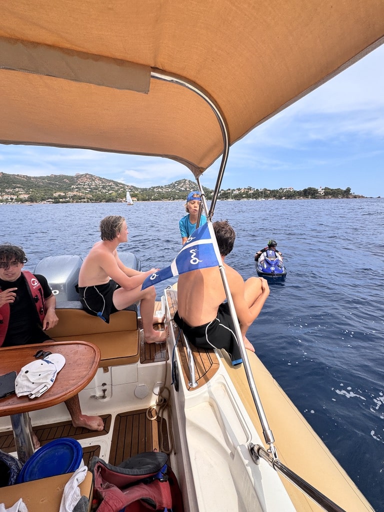 Balade en bateau et jet ski sur la côte méditerranéenne Jeunes sur un bateau de plaisance en mer, jet ski à proximité et vue sur la côte méditerranéenne ensoleillée.