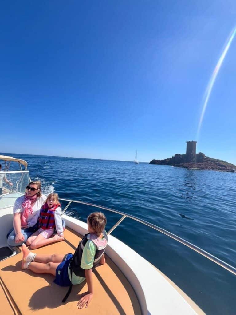 Balade en famille en bateau à l'Île d'Or, Méditerranée Famille en bateau devant la tour de l'Île d'Or à Saint-Raphaël, mer Méditerranée et ciel bleu ensoleillé.