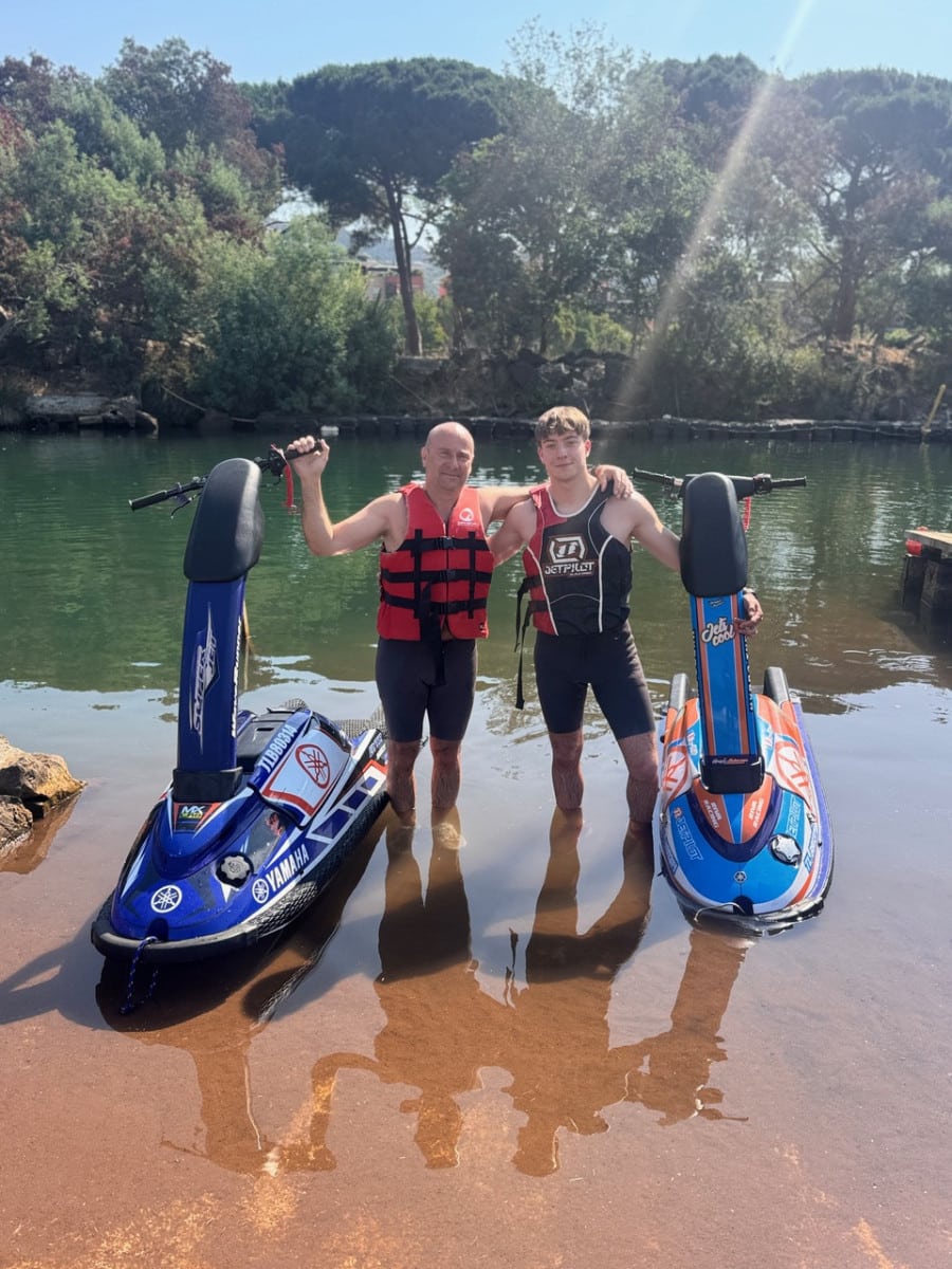 Deux hommes posent fièrement avec leurs jet-skis Yamaha dans une eau calme et ensoleillée.