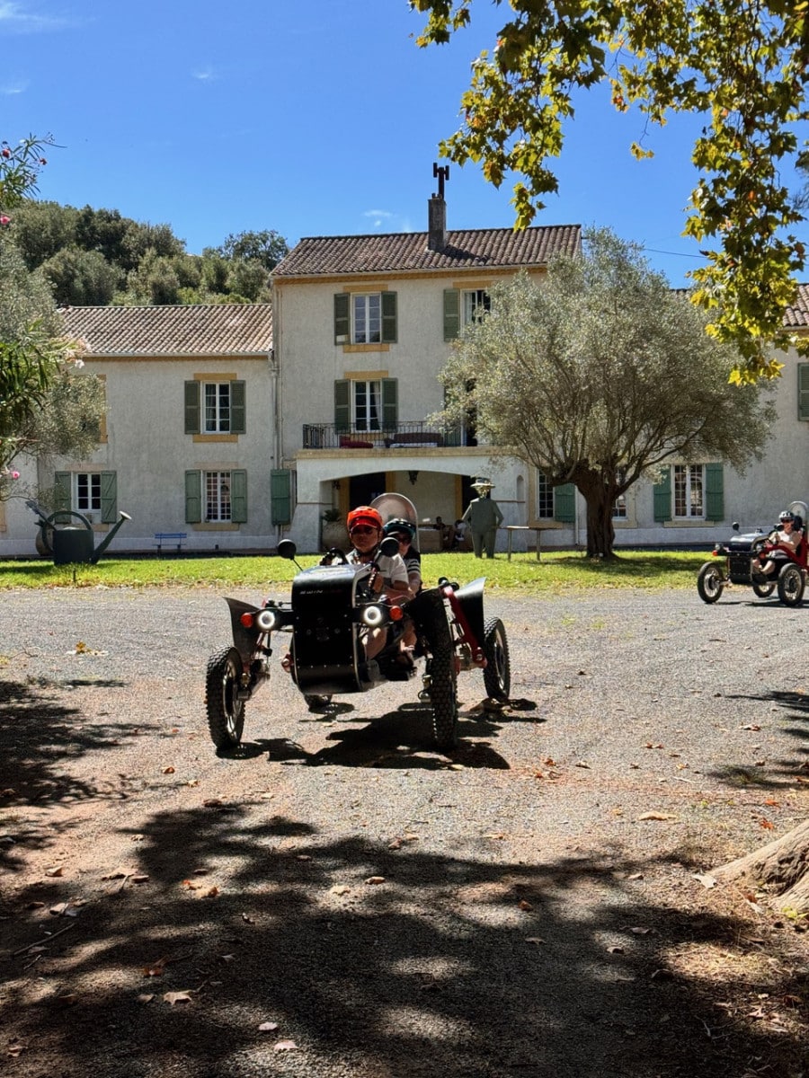 Randonnée en Swincar électrique devant une bastide provençale traditionnelle lors d'une journée ensoleillée.