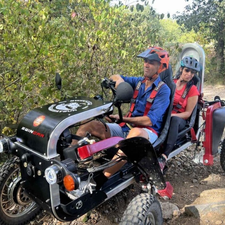 Swincar Électrique : Aventure Tout-Terrain et Randonnée Couple pilotant un Swincar électrique articulé sur un sentier escarpé en pleine nature.